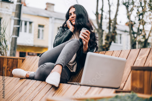 Happy latin woman with smartphone or laptop in city centre