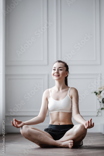 Young woman doing yoga at home in the lotus position. Free Download Young woman doing yoga at home in the lotus position. - GFXLoad