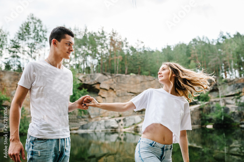 Young couple going near lake. Man and woman going on background of rocks and stone . Landscape of an old industrial granite quarry. Close up. half length. upper half. © Serhii