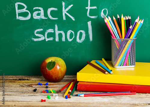Back to school supplies. Books and blackboard on wooden background