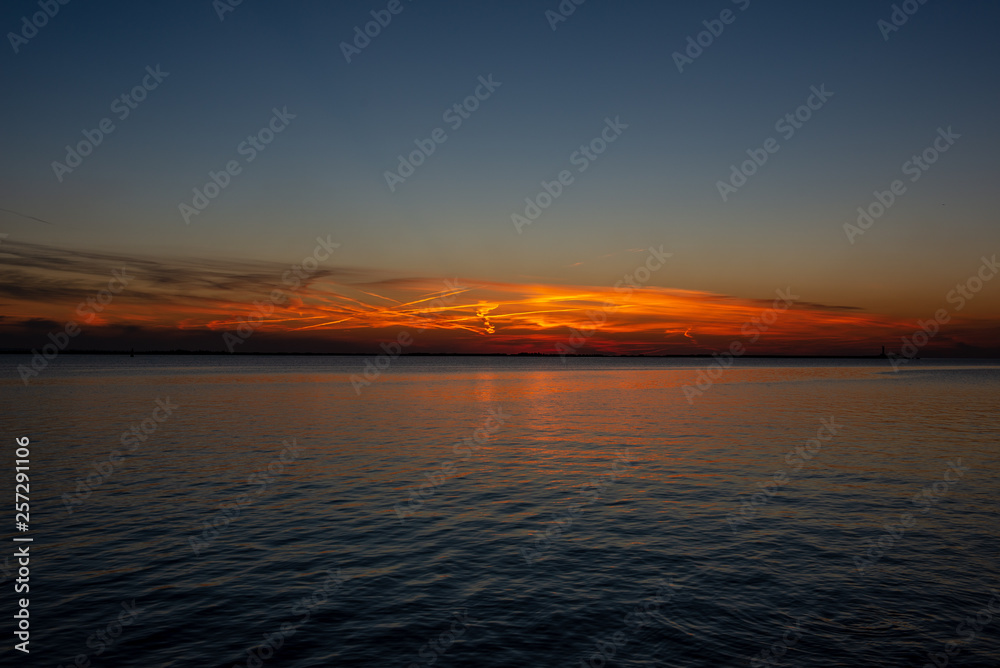 Naklejka premium dramatic sunset over sea beach with rocks and stormy water