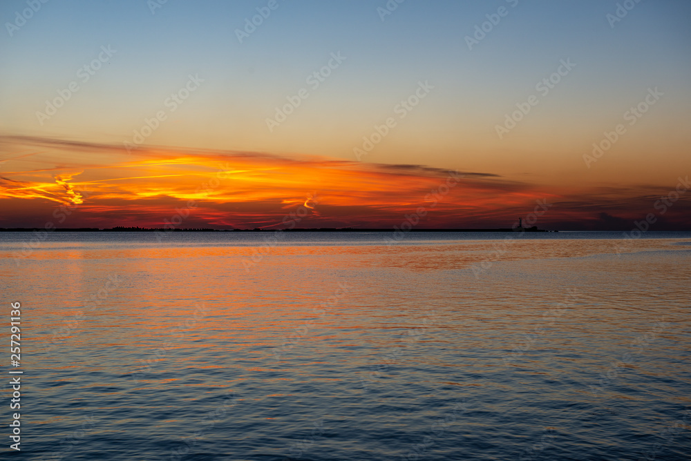 dramatic sunset over sea beach with rocks and stormy water