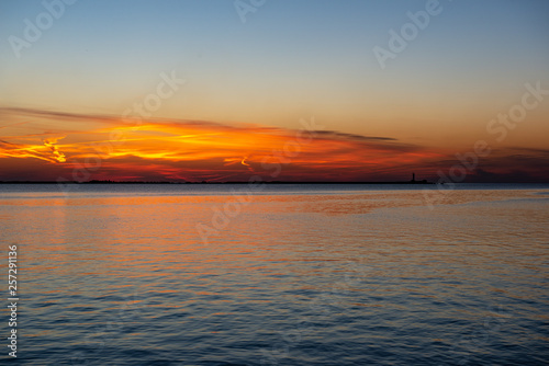 dramatic sunset over sea beach with rocks and stormy water