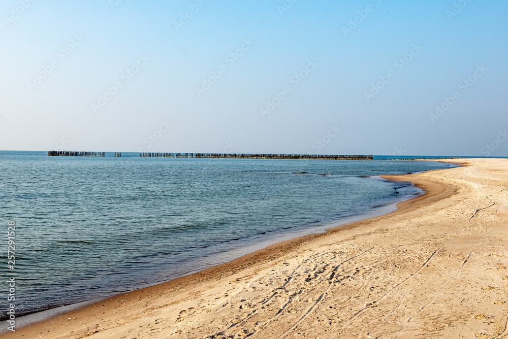 calm sea beach in summer with large rocks and wooden poles from old breakewater in the sea calm sea beach in summer with large rocks and wooden poles from old breakewater in the sea