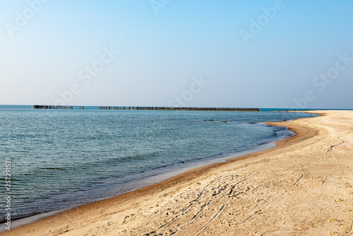 calm sea beach in summer with large rocks and wooden poles from old breakewater in the sea