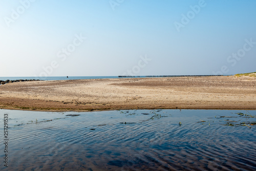 calm sea beach in summer with large rocks and wooden poles from old breakewater in the sea photo