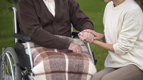 Female holding aged male hand, visiting granddad in hospital, nursing home