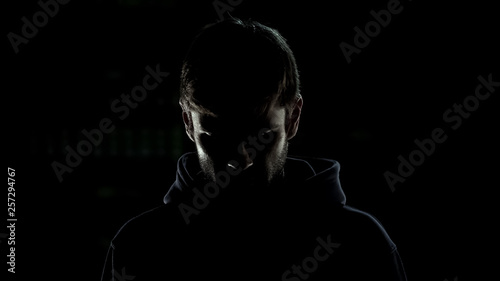Silhouette of criminal regretting wrong decisions isolated on black background