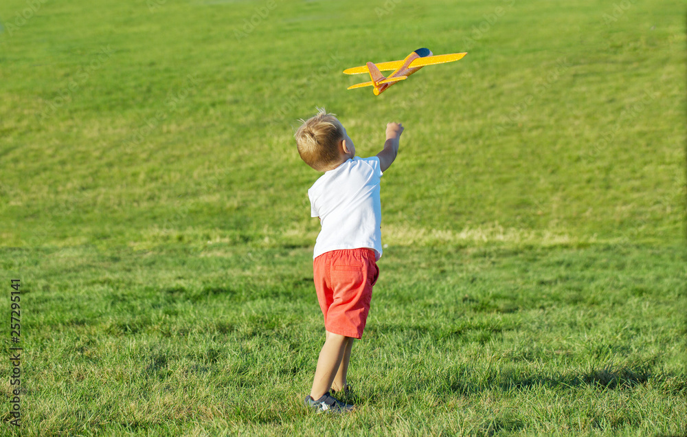 Young boy playing airplane on the green grass Young boy playing airplane on the green grass