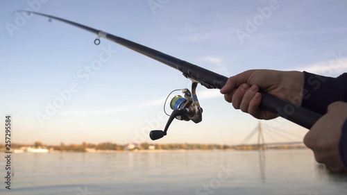 Spinning rod closeup, man fly-fishing near river, active leisure, weekend