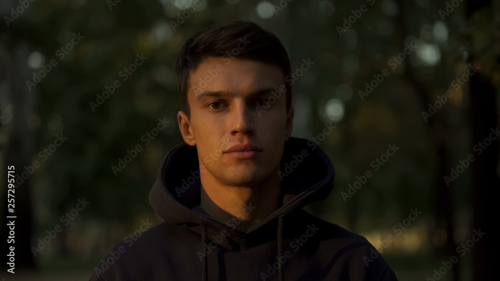 Young man looking at camera, half shadowed face, good and evil fight concept Young man looking at camera, half shadowed face, good and evil fight concept