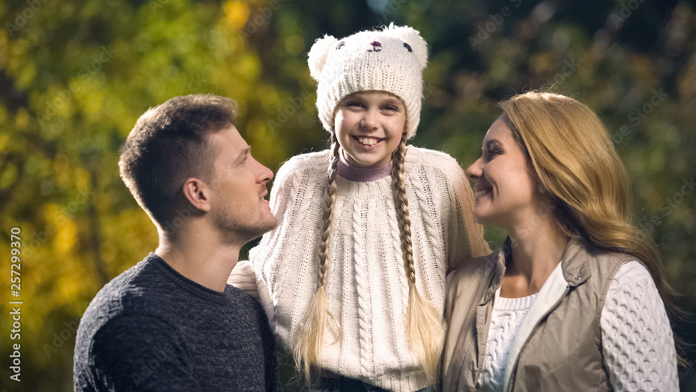 Family with smiling daughter posing for camera in fall park, health insurance Family with smiling daughter posing for camera in fall park, health insurance