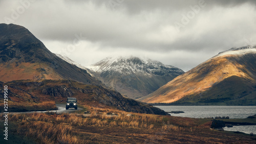 SUV on road in mountain landscape on cloudy day