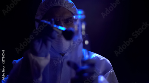 Criminalist taking fingerprints from bottle at crime scene, search for evidence