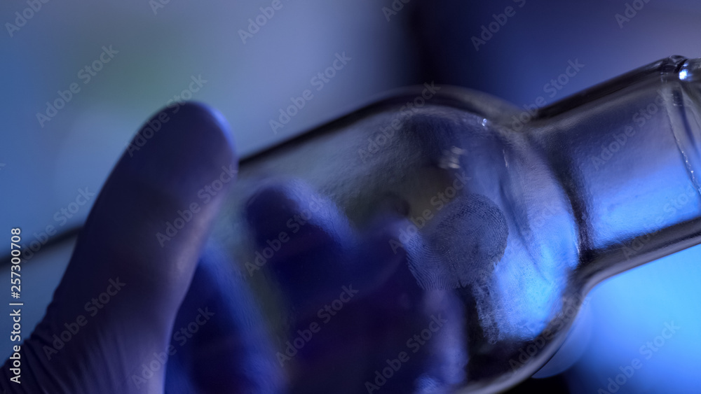 Forensic science expert holding bottle with fingerprints closeup, identification