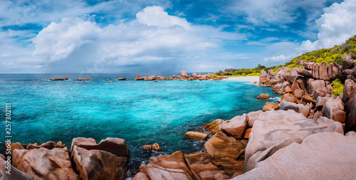Beautiful panorama with impressive white fluffy clouds wild rocky beach Anse Marron in Seychelles. La Digue