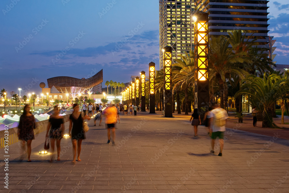 Obraz premium Barcelona - coastline with beach during evening and night, people on promenade, lights and hotels
