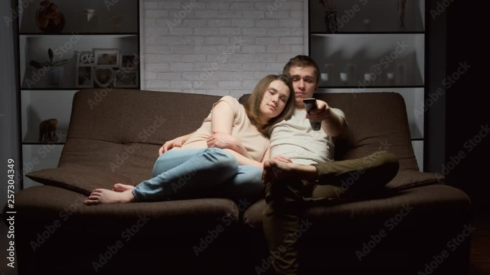 Young people are ready to start watching TV sitting on the sofa in the living room. Young people are ready to start watching TV sitting on the sofa in the living room.