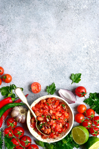 Fototapeta Naklejka Na Ścianę i Meble -  Tomato salsa (salsa roja) - traditional mexican sauce  with ingredients for making on a light grey slate,stone or concrete background.Top view with copy space.