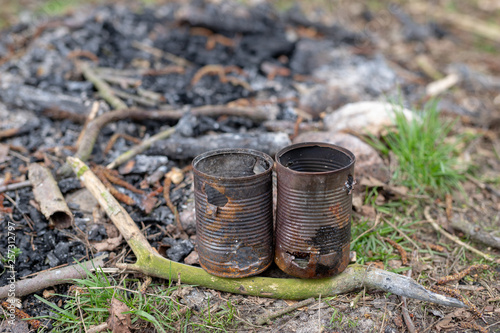 Old rusty cans in a campfire. Place for camping in the forest.