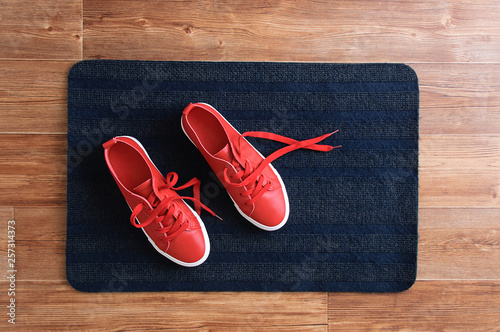 Red sneakers stand on a gray rug. View from above. photo