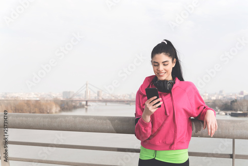 Young sporty woman holding smartphone
