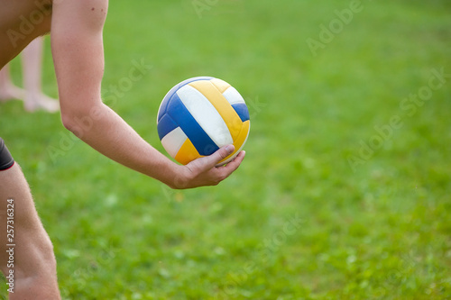 Teen boy playing beach volleyball. Volleyball player on the grass playing with the ball, a volleyball ball in his hand.