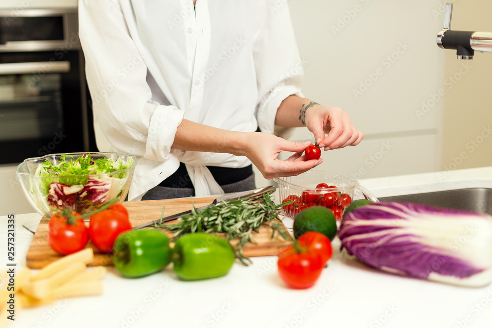 Brunette woman on the kitchen preparing healthy nutrition salad from fruits and vegetables. Housewife concept