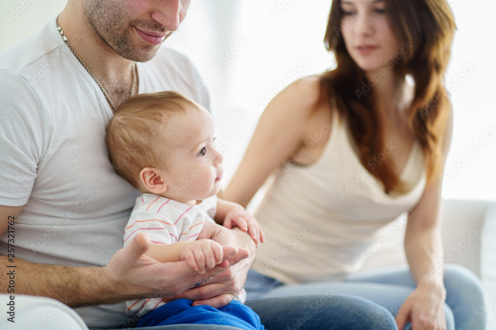 Happy young family enjoy time together. Mom, dad and little baby son resting in living room. Childhood, parenthood, togetherness, love, happiness concept Happy young family enjoy time together. Mom, dad and little baby son resting in living room. Childhood, parenthood, togetherness, love, happiness concept