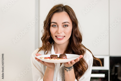 Brunette woman cooking and eating red meat steak with glass of red wine. Housewife concept