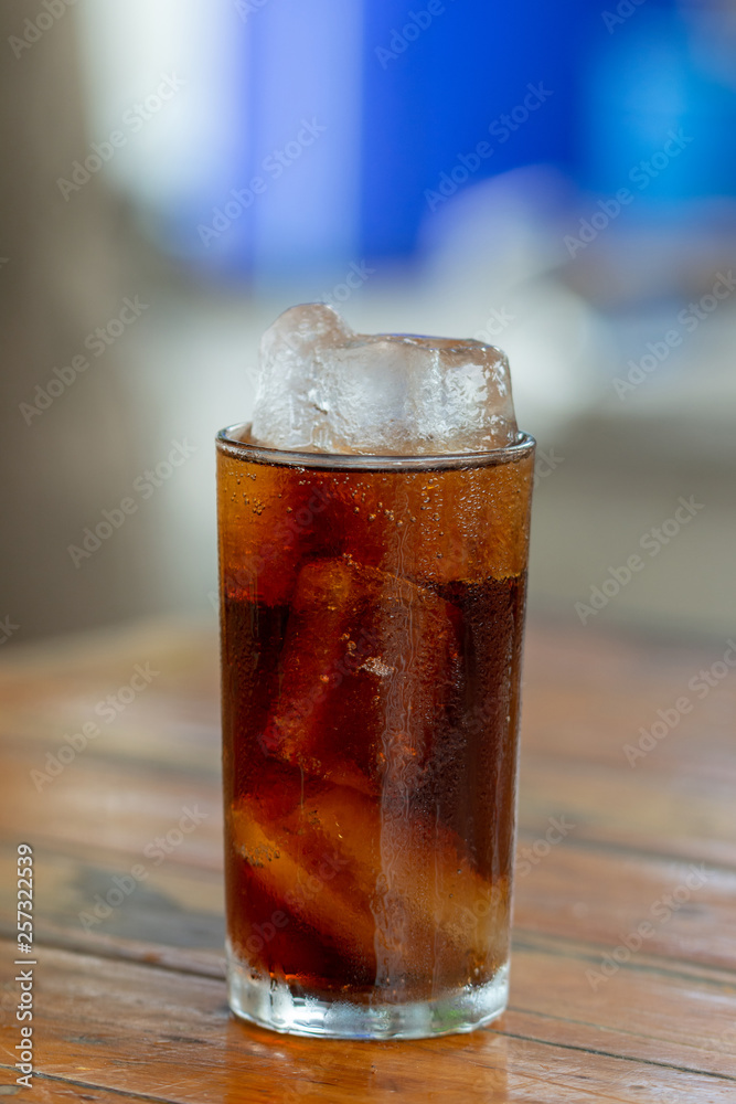 Cola soda with ice in glass on wooden table Cola soda with ice in glass on wooden table