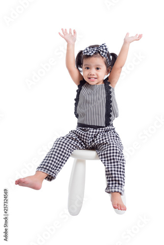 Little asian girl sitting on chair and pushing hand up with smiles over white background