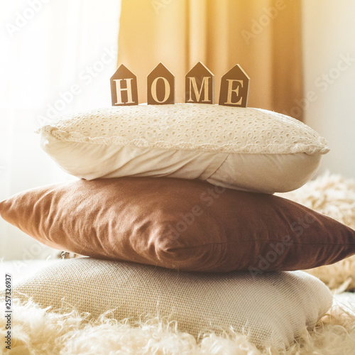 Fototapeta Naklejka Na Ścianę i Meble -  A lot of decorative cozy pillows and the inscription HOME