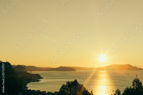 Gorgeous picturesque landscape of seashore with hills, sun is shining, sunrise