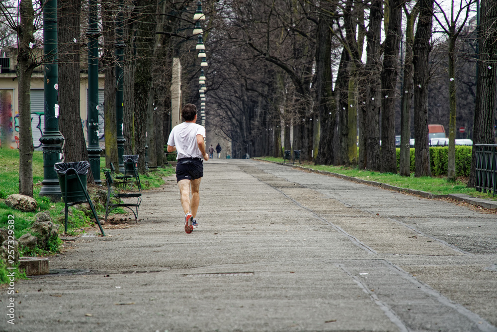 Fototapeta premium Man jogging outdoors in public park, running for health.