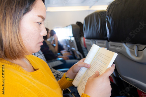 asian woman reading book on plane