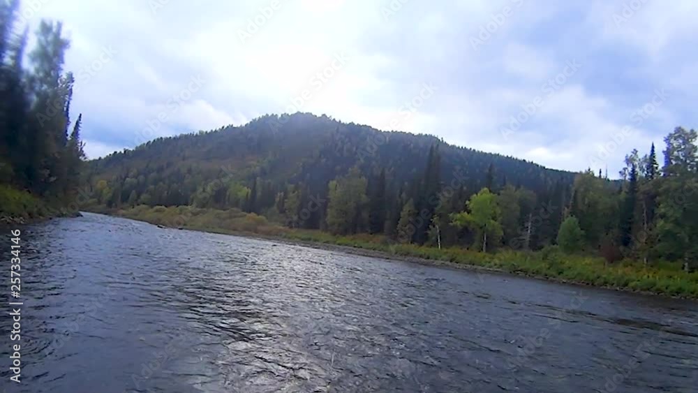 Fishing rod fishing in the river, against the mountains covered with green trees in the daytime on a summer day Fishing rod fishing in the river, against the mountains covered with green trees in the daytime on a summer day