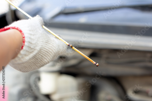 Auto mechanic checking the car engine oil level..Close up mechanic hand repairing car with open hood, mechanical checking motor lubricant level, car maintenance fixing service in workshop garage.
