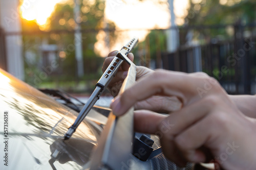 Man hand picking up car windscreen wiper..Technician changing windshield wipers blade outdoor..Mechanic check, replacing old wiper blade on customers car front window glass at car station