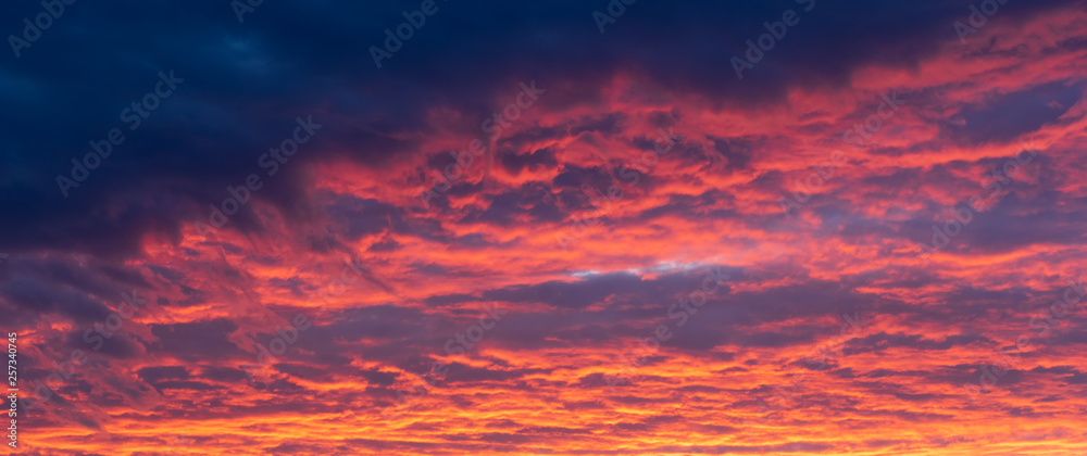Fiery red clouds, light rays and other atmospheric effect at sunset or sunrise