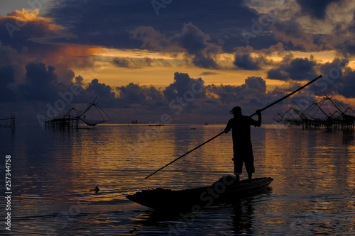 Silhouette of Local fisherman started his work early morning, in the golden sunrise in the wetland Talay Noi, Pattalung Province, Thailand. © Attapol