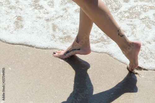Piedi femminili con tattoo in acqua photo