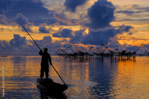 Silhouette of Local fisherman started his work early morning, in the golden sunrise in the wetland Talay Noi, Pattalung Province, Thailand. © Attapol