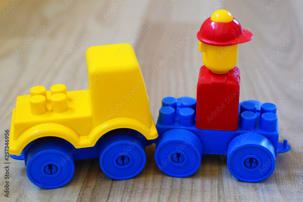Toy car made of colorful plastic blocks on wooden texture floor background. Concept of educational and developing toys for children. Toy car made of colorful plastic blocks on wooden texture floor background. Concept of educational and developing toys for children.