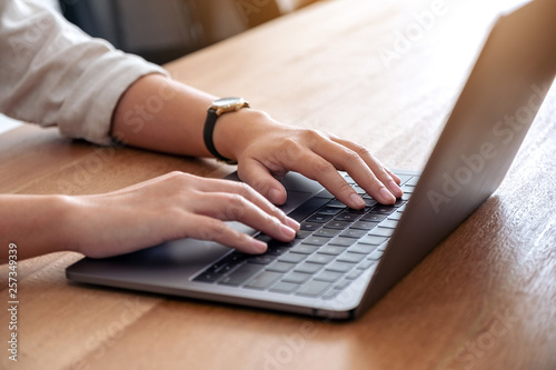Closeup image of woman's hands using and typing on laptop keyboard on the table