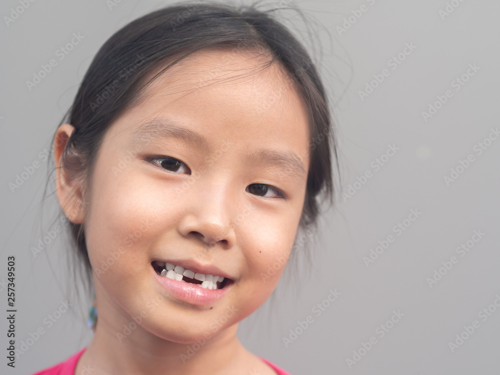 Asian little cute girl smile with her broken tooth , grey background Asian little cute girl smile with her broken tooth , grey background
