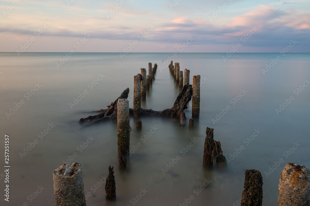 Long exposure shot sunset seascape with mortar of broken bridge.