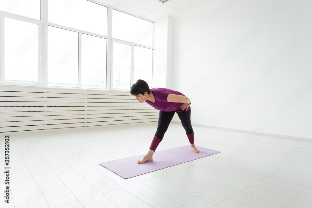 Sport, yoga, people concept - Sporty middle-aged woman practicing yoga indoors