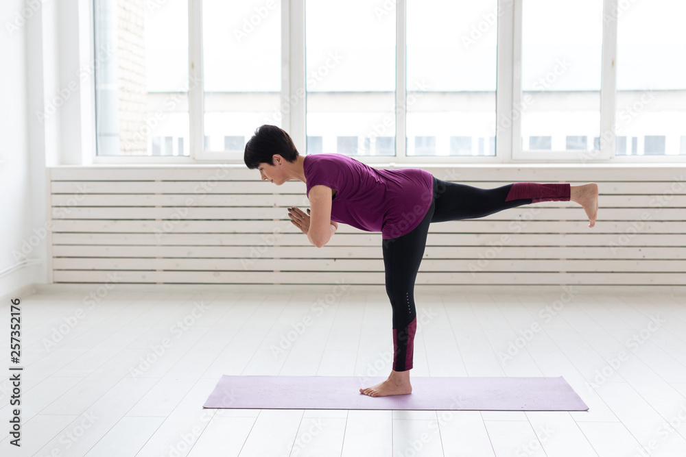 Yoga, people concept - a middle-aged woman doing a yoga and try to do a asana Yoga, people concept - a middle-aged woman doing a yoga and try to do a asana