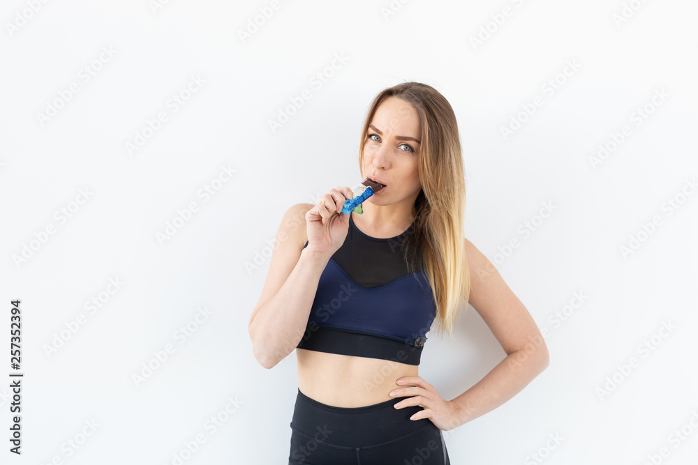 Attractive sporty fitness woman holding a protein bar on white background Attractive sporty fitness woman holding a protein bar on white background